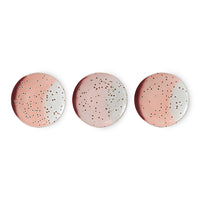 Three round ceramic plates with speckled design on a white background