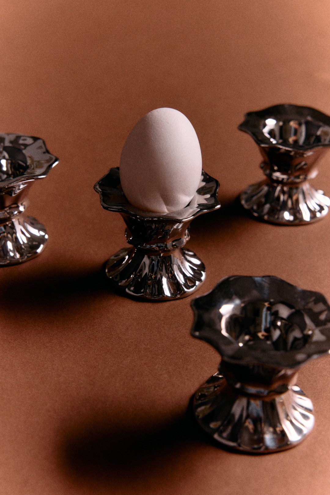 silver egg cups with a white egg an a brown backround