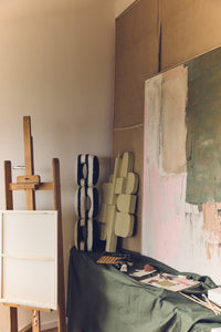 Art studio with easel, sculptures, and abstract paintings on a wall.