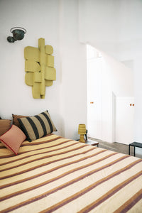 Bedroom with striped bedding and a wall-mounted lamp
