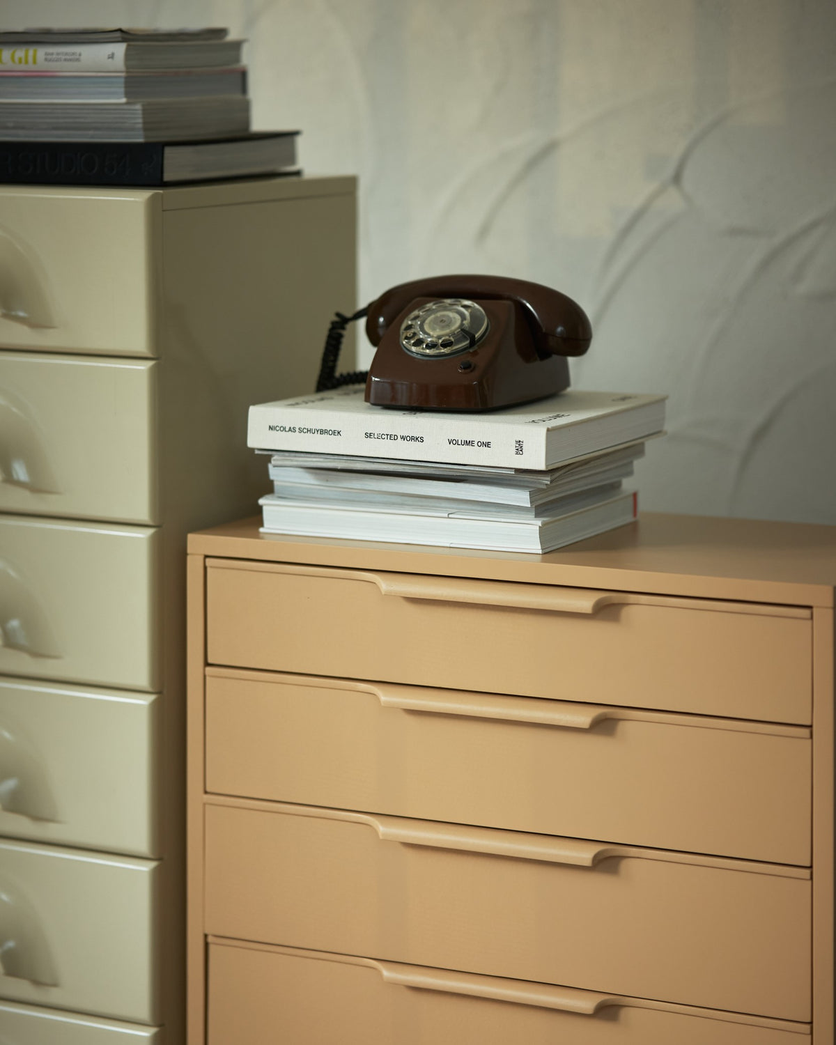 wooden chest of drawers in camel color with brown rotary phone and books