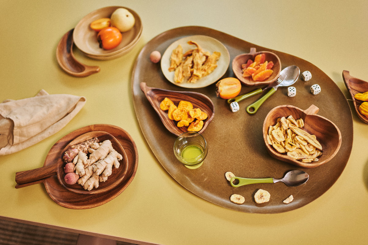 wooden bowl in shape of apple with dried bananas on yellow table