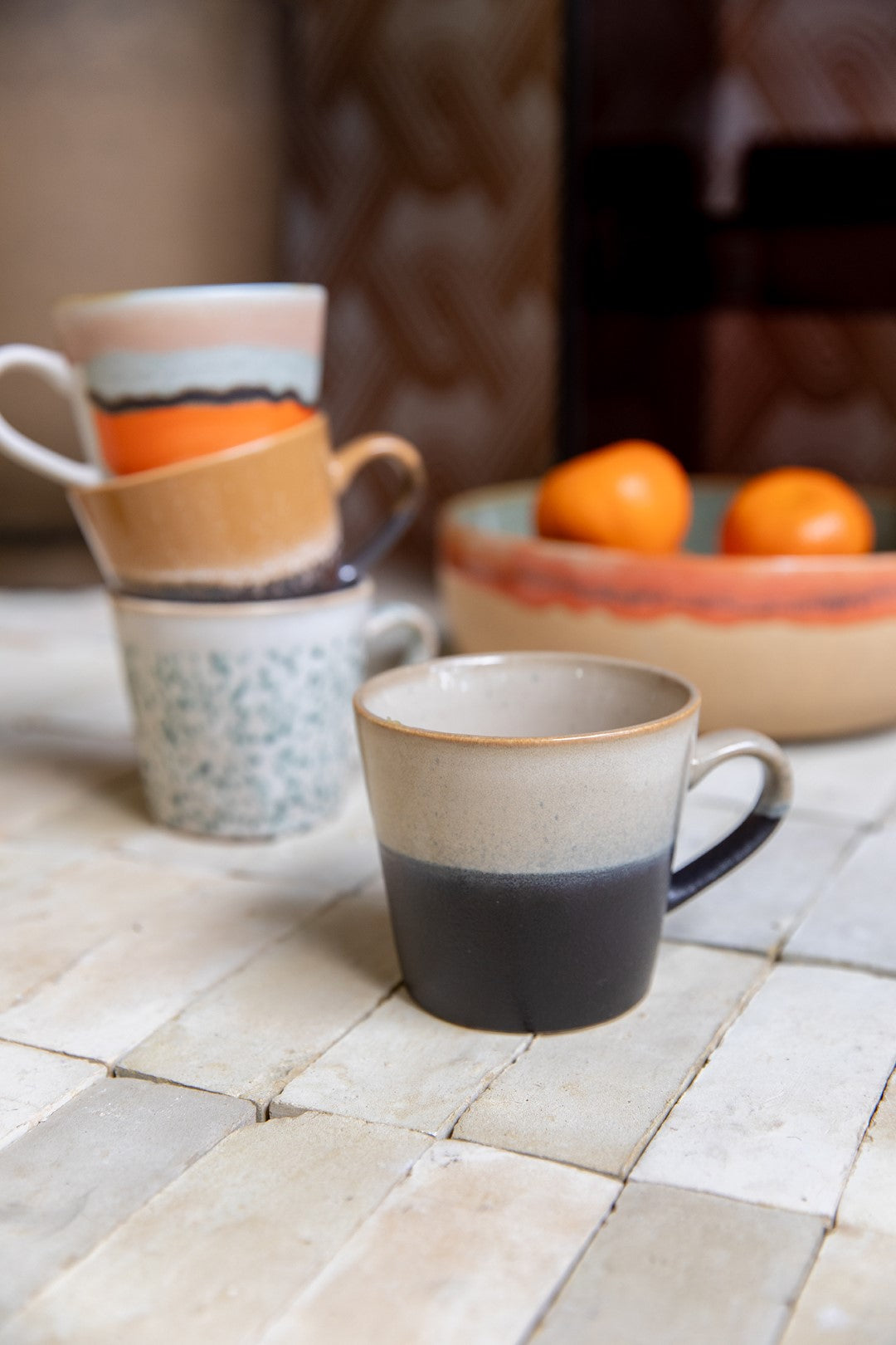 multi colored mugs with ear on tile counter top