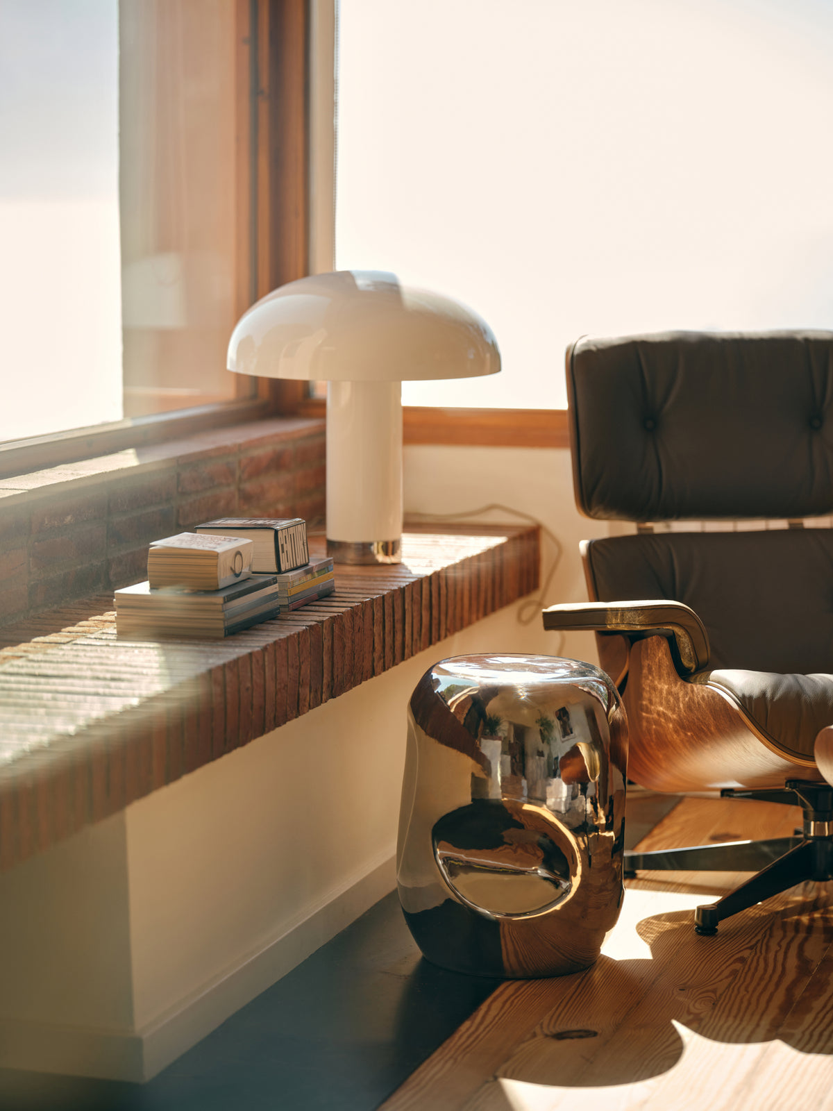 shiny silver accent table next to Eames Chair