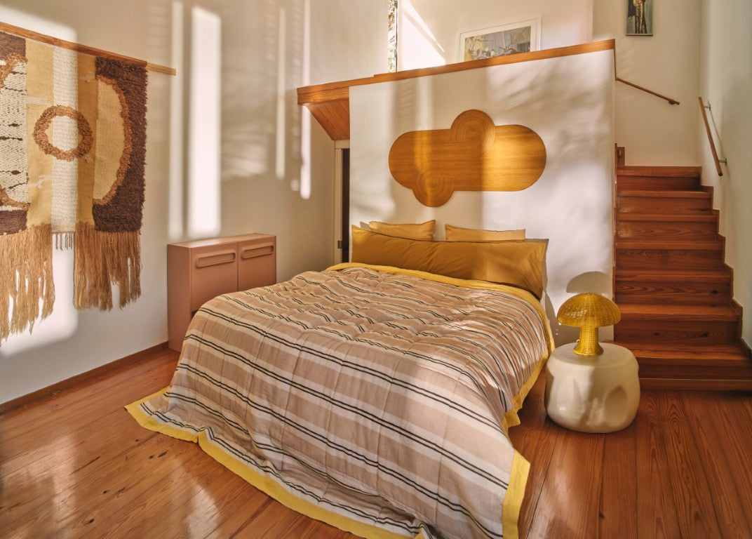 bedroom with striped duvet and ceramic side table as nightstand