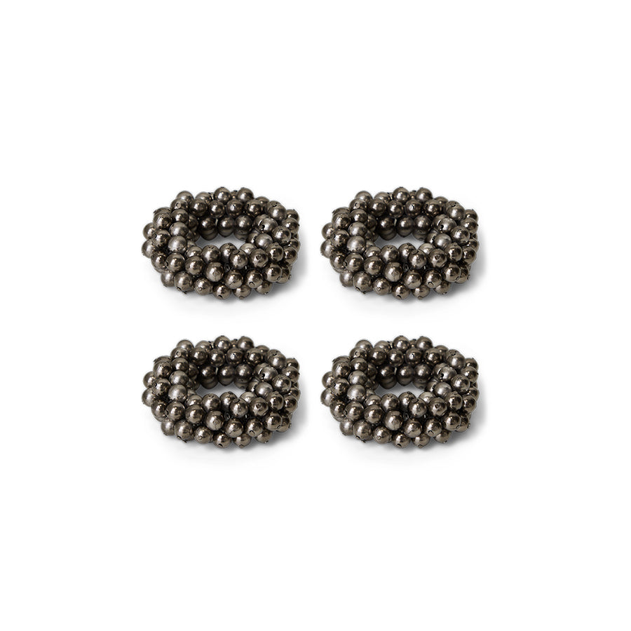 Four metallic beaded circular napkin rings on a white background