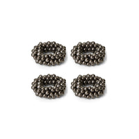 Four metallic beaded circular napkin rings on a white background