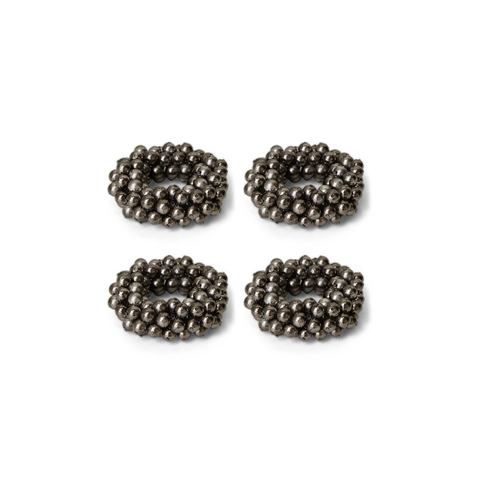 Four metallic beaded circular napkin rings on a white background