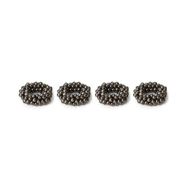 Four metallic beaded napkin rings on a white background