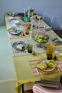 Dining table set for a meal with colorful tablecloth, plates, and glasses.
