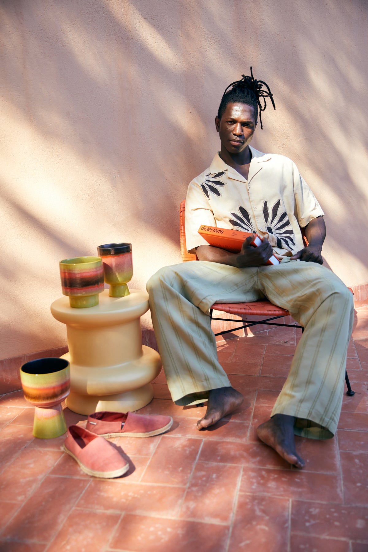 flower pots on foot on side table with man holding a book