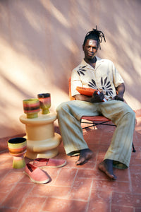 flower pots on foot on side table with man holding a book