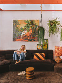 dark brown and orange striped velvet lumbar pillow on brown sofa in retro style