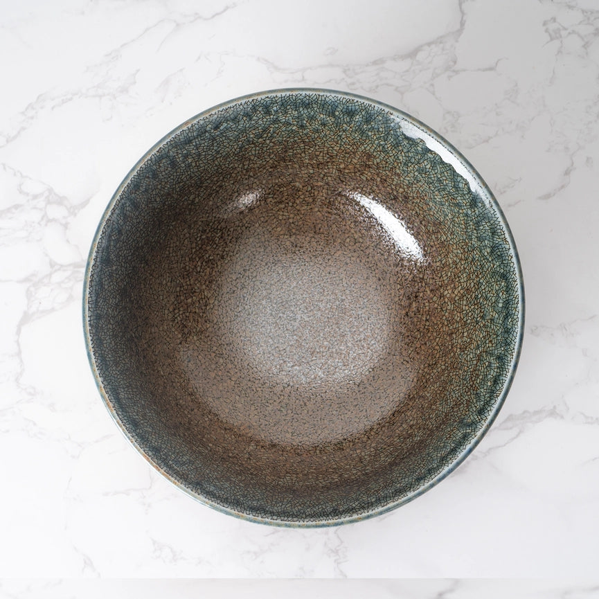 Ceramic bowl with a speckled glaze on a marble surface