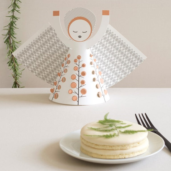 Small cake on a plate with a decorative angel figurine in the background