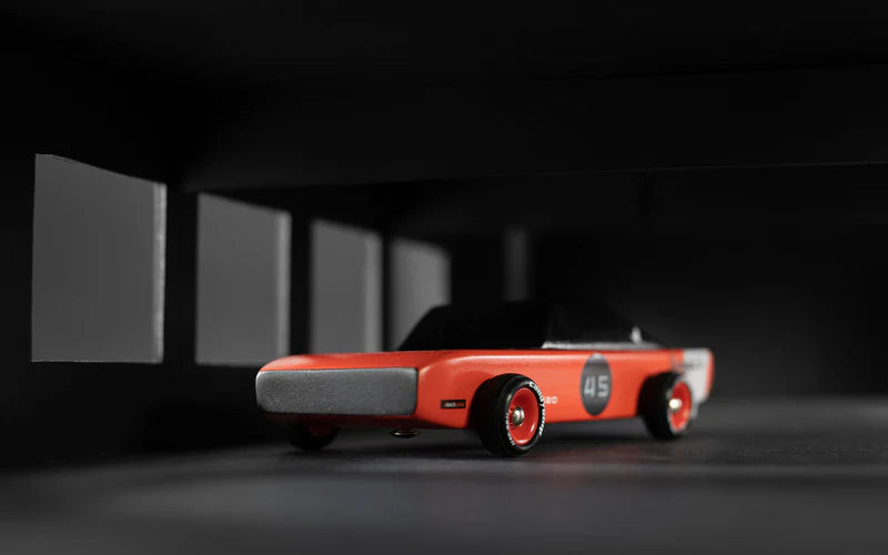 Red toy car with a black hood on a dark background