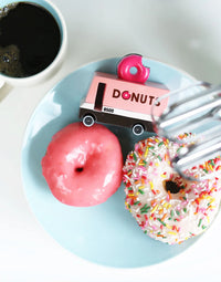 Donuts on a plate with a 'Donuts' truck toy and a cup of coffee.
