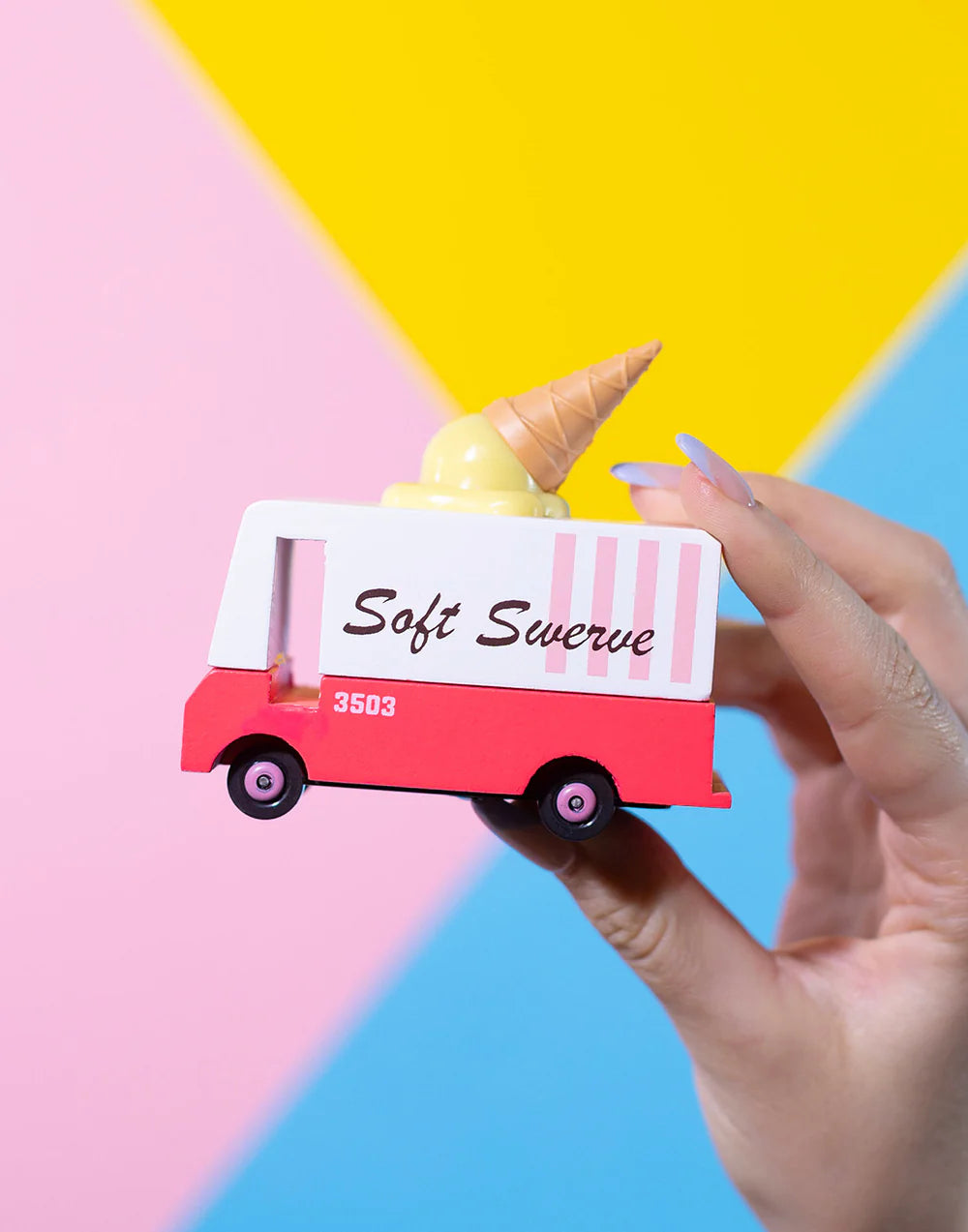 Small model of a ice cream truck with a cone on top against a colorful background