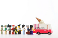 Model ice cream truck with 'Soft Serve' text and a line of  Lego people waiting, on a white background