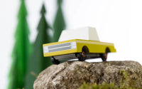 Toy car on a rock with blurred greenery in the background