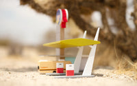 Toy gas station and car on a sandy surface with a blurred background