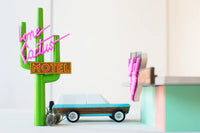 Model of a vintage car next to a neon cactus sign with 'Lone Cactus Motel' text on a white background.