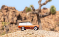 Model of a vintage camper van on a rocky outcrop with desert landscape in the background