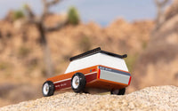 Toy vehicle on a sandy surface with a desert landscape in the background