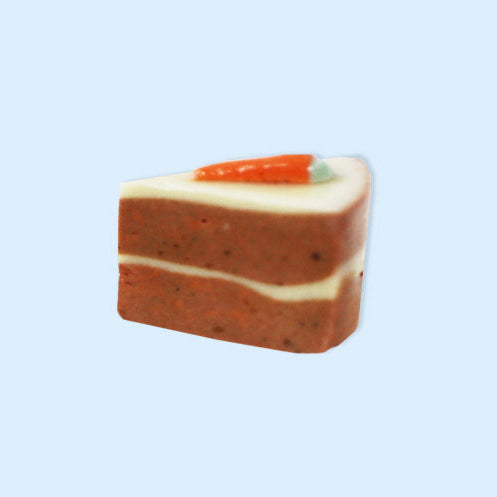 Triangular slice of carrot cake with a decorative carrot on a light blue background