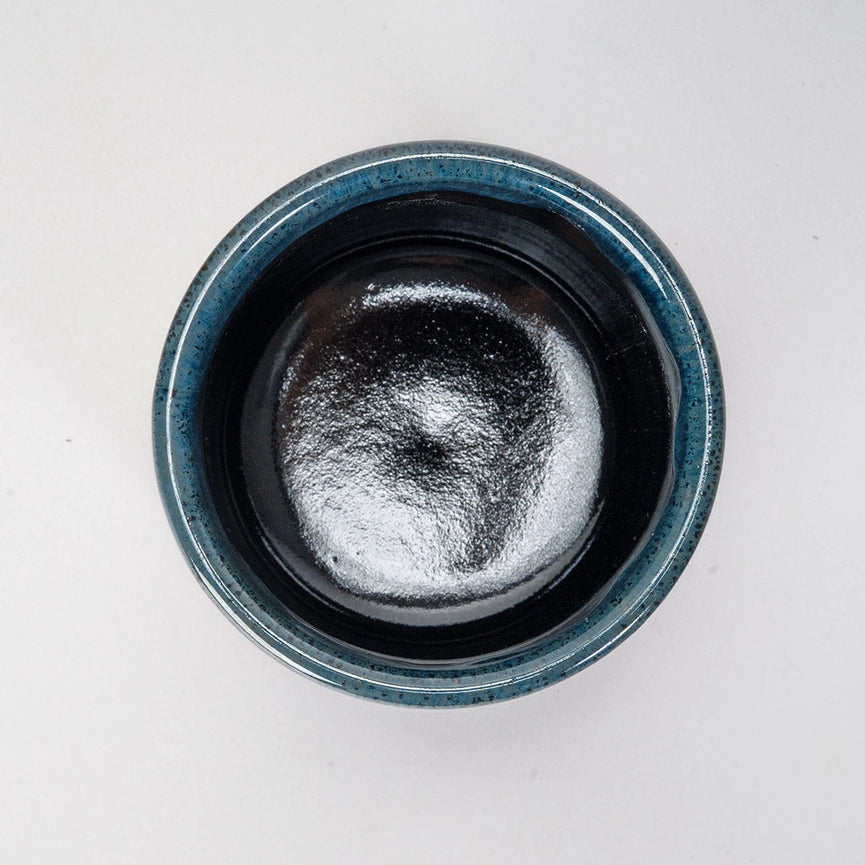 Blue and black ceramic container with a black interior on a white background
