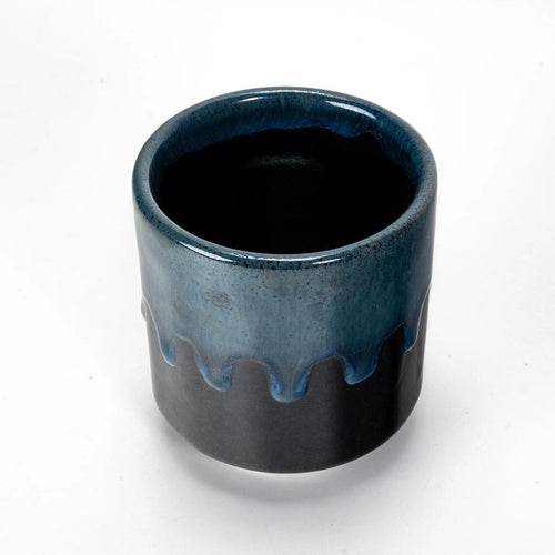 Blue and black ceramic cup with textured design on a white background