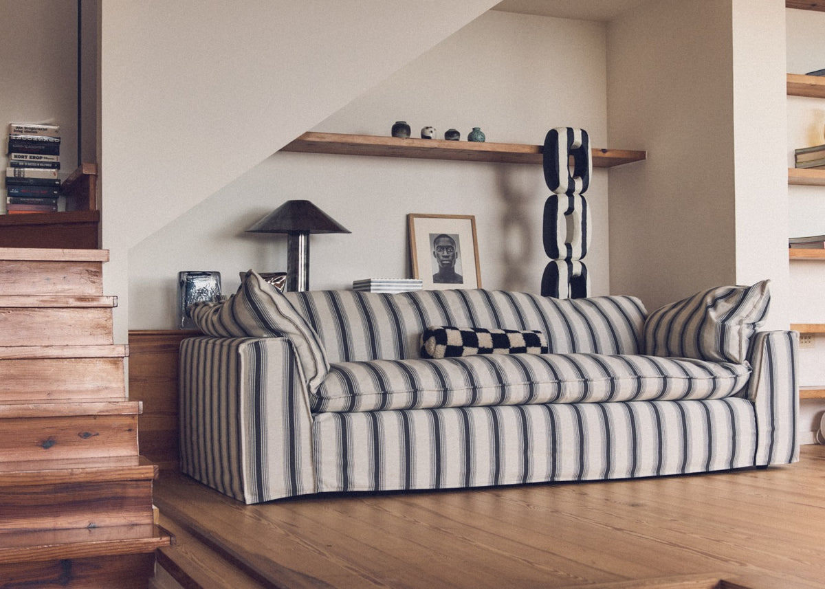 Striped sofa in a living room with wooden floor and shelves.