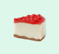 Slice of cheesecake with red fruit topping on a light green background