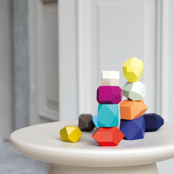 Colorful geometric wooden blocks on a white surface with a neutral background