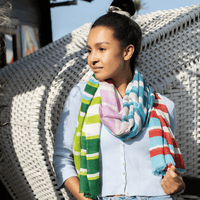 Woman wearing a colorful striped scarf sitting on a wicker chair.