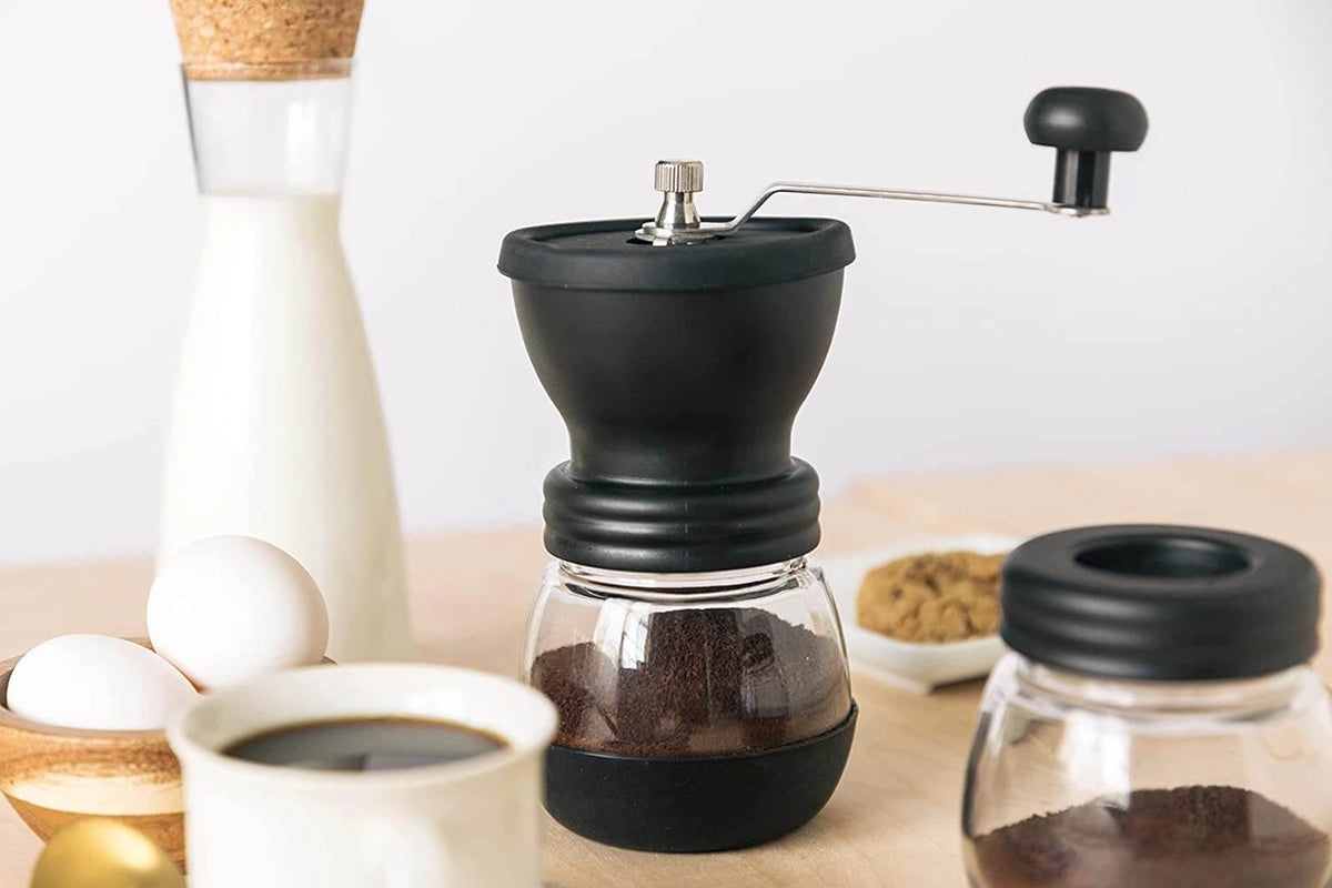 Hand coffee grinder with coffee beans on a wooden table