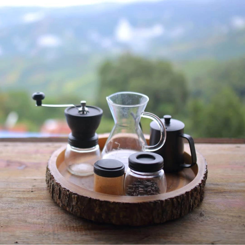 Coffee-making setup on a wooden tray with a scenic background