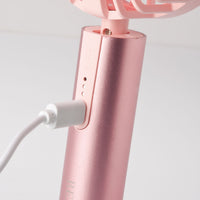 Pink fan with white cord on a light gray background