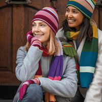 Two people wearing colorful winter hats and scarves sitting together.
