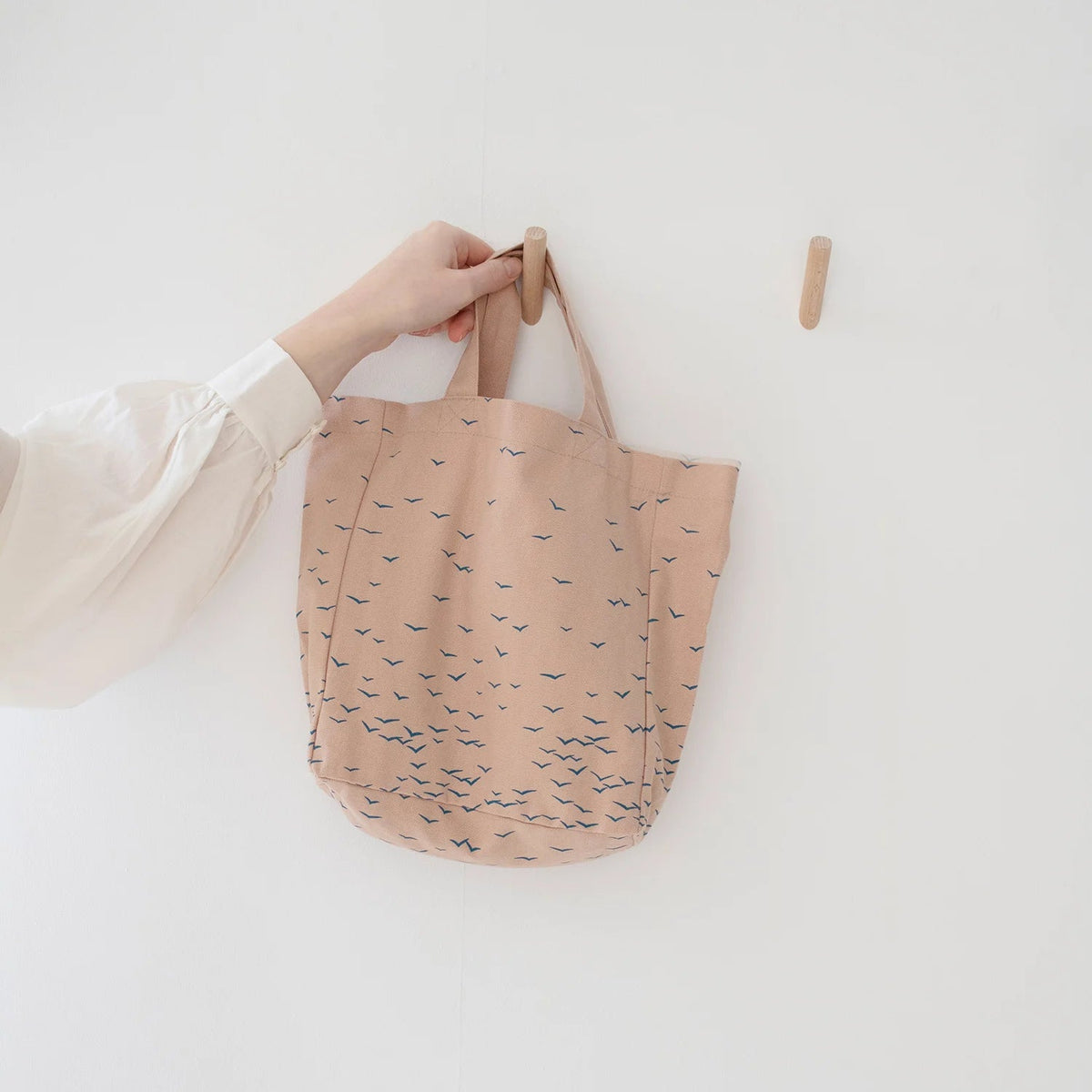 Person holding a pink tote bag with blue patterns against a white background