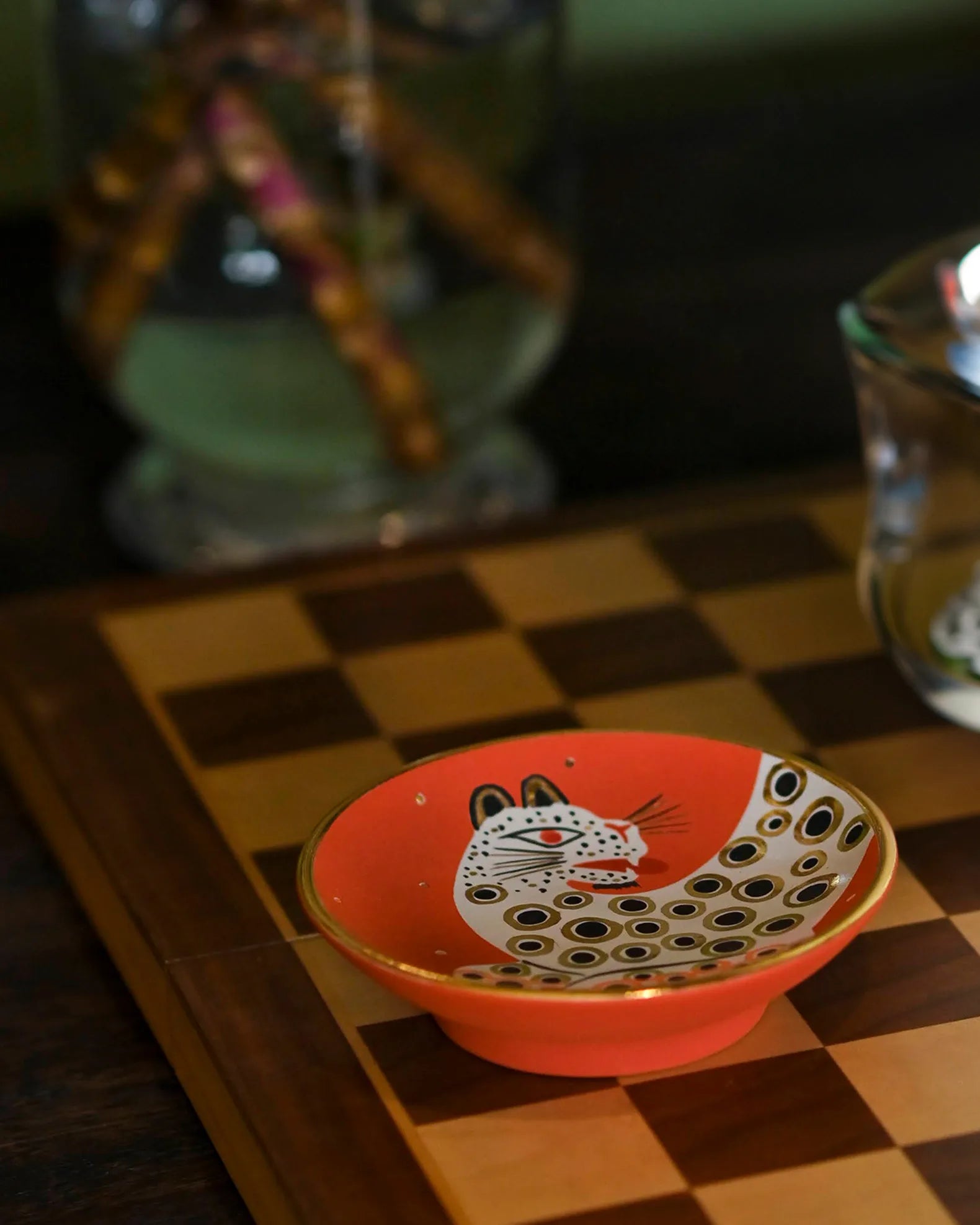 Small orange dish with a cat design on a checkered surface