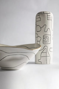 Two ceramic pieces with abstract line designs on a white background