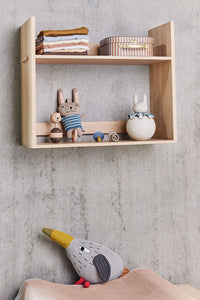 Wooden shelf with toys against a concrete wall