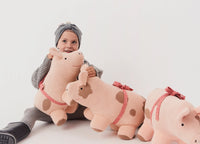 Child holding a plush cow toy with a plain background