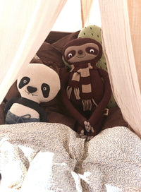 Two plush toys, a panda and a sloth, sitting together with a soft blanket underneath.