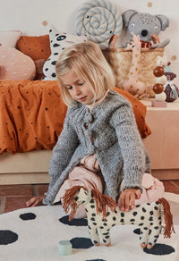 Child playing with a toy horse in a cozy room with soft lighting