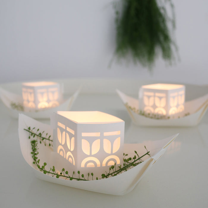 Decorative white paper boats with cut-out patterns on a light background