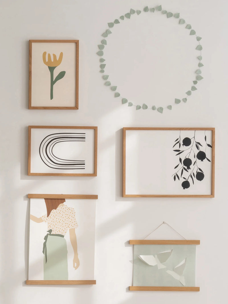 green paper leave wreath on wall with art works in wooden frames