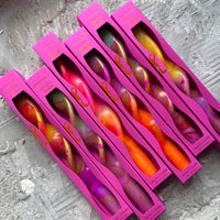 Pink packaging of scented candles with visible branding on a gray surface