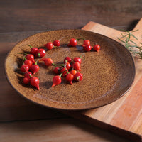 Red chili peppers on a brown ceramic plate on a wooden surface